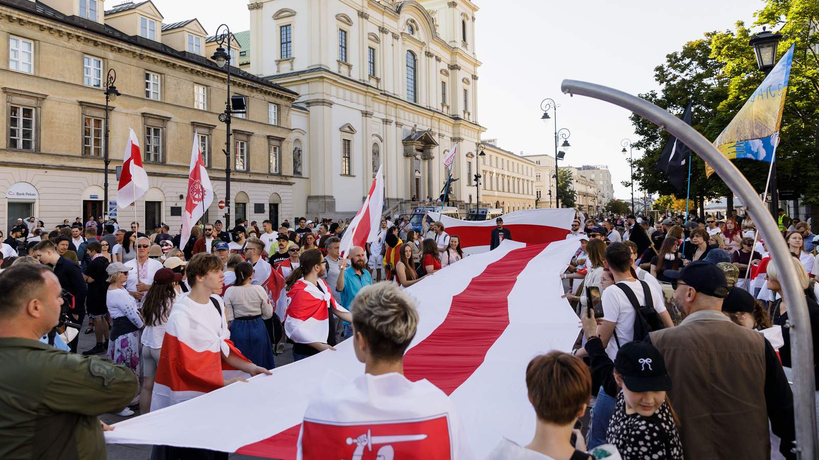 Участники митинга, посвященного шестой годовщине президентских выборов в Беларуси 2020 года, держат большой белорусский бело-красно-белый национальный флаг. Варшава, Польша. 9 августа 2026 года. Фото: SOPA Images Limited / Alamy Live News / Vida Press