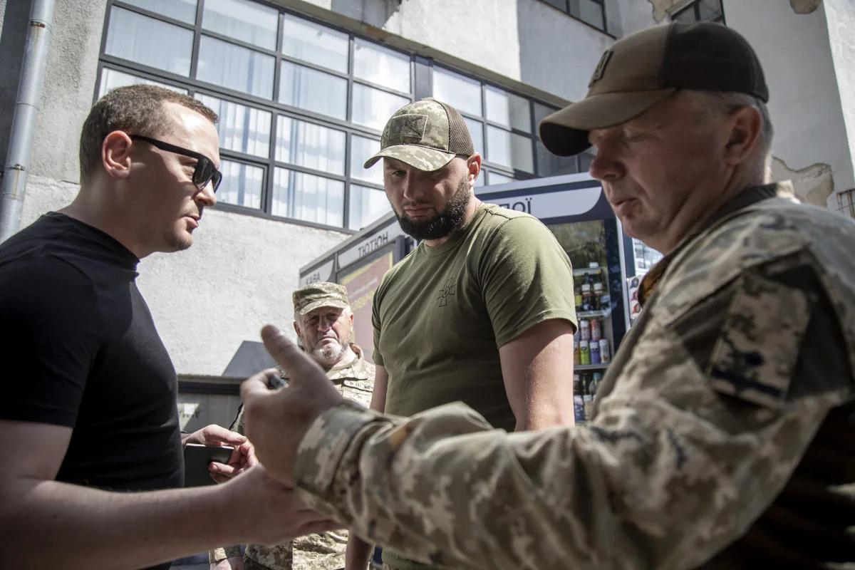 Сотрудники центра комплектования и социальной поддержки, отвечающие за мобилизацию в Украине, проверяют документы у мужчин в центре Харькова, 8 августа 2024 года. Фото: Narciso Contreras / Anadolu / Abaca Press / ddp images / Vida Press