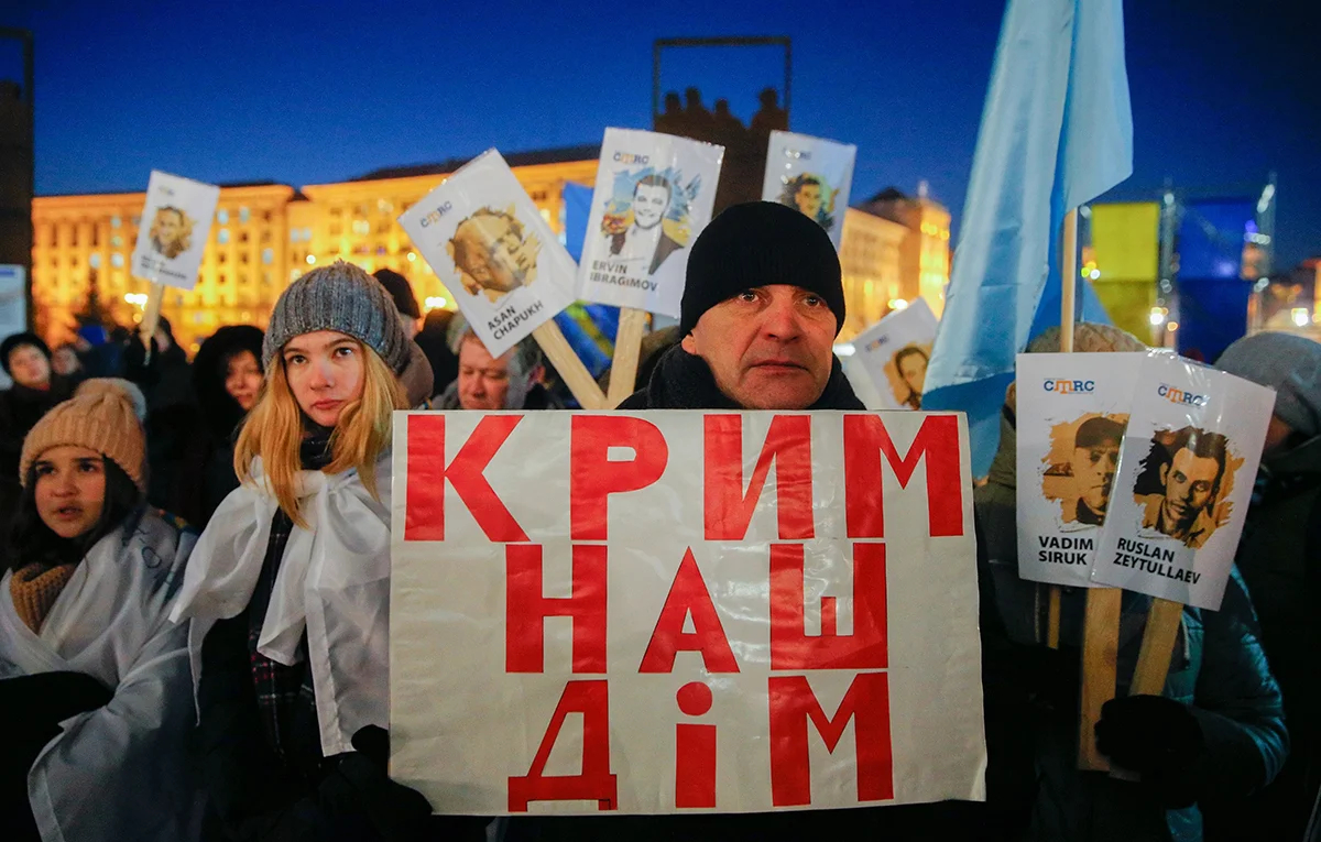 Украинские и крымскотатарские активисты держат плакат с надписью «Крым — наш дом!» и плакаты с именами людей, которые поддерживали Украину и пропали без вести или были арестованы российскими властями в Крыму, во время акции «Солидарность 26» на площади Независимости в Киеве, Украина, 26 февраля 2018 года. Фото: Сергей Долженко / EPA-EFE