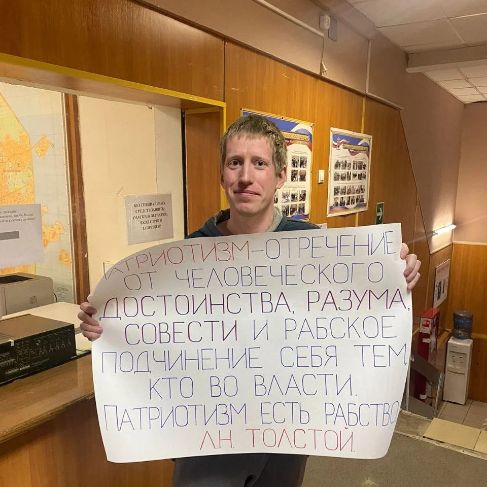 Алексей Никитин держит плакат в полицейском отделе после задержания, 24 марта 2022 года. Фото из личного архива героя