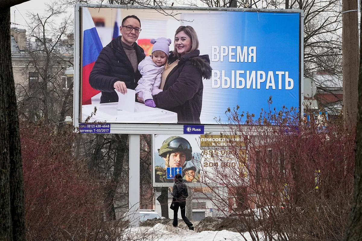 Женщина проходит мимо рекламных щитов о президентских выборах и службе по контракту, Санкт-Петербург, Россия, 7 марта 2024 года. Фото: Дмитрий Ловецкий / AP / Scanpix / LETA