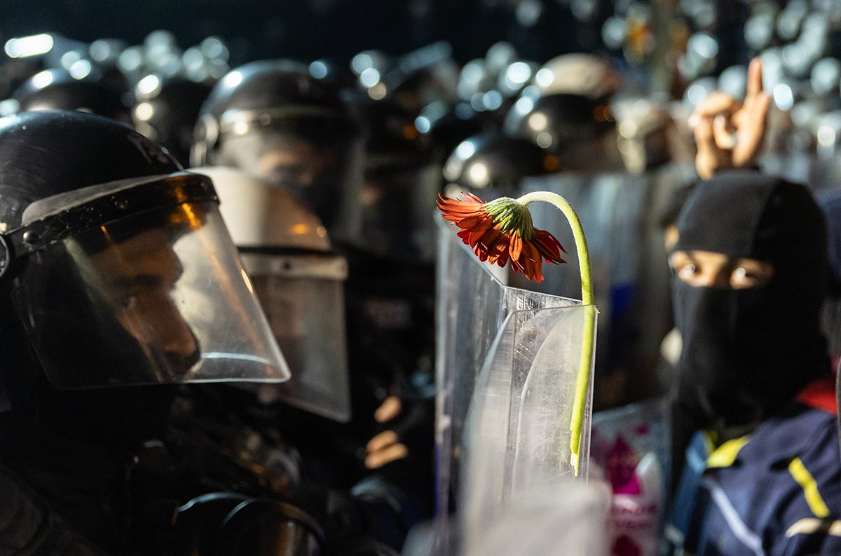 Протестующий прикрепил цветок к щиту полицейского во время акции протеста против задержания мэра Стамбула Экрема Имамоглу в Стамбуле, Турция, 24 марта 2025 года. Фото: Erdem Sahim / EPA-EFE