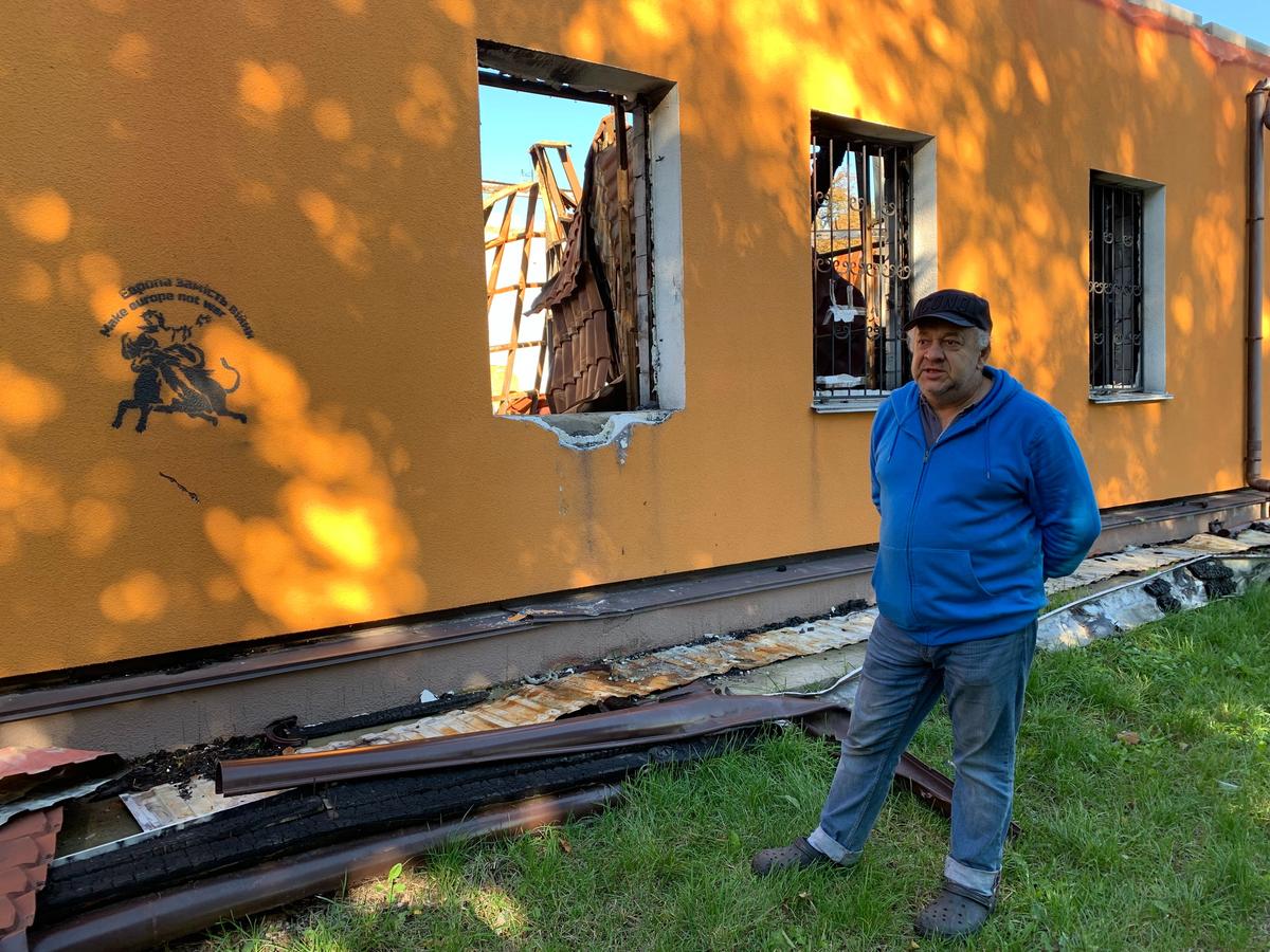 Частный предприниматель и депутат поселкового совета Руслан Стоколос возле разрушенного Иванковского историко-краеведческого музея. На уцелевшей стене трафарет с надписью "Make Europe not war". Фото: Ольга Мусафирова, «Новая газета Европа»