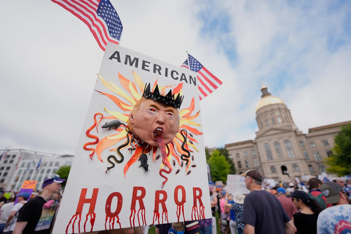 Участник акции держит плакат с изображением Трампа в Атланте, Джорджия, 14 июня 2025 года. Фото: Mike Stewart / AP Photo / Scanpix / LETA